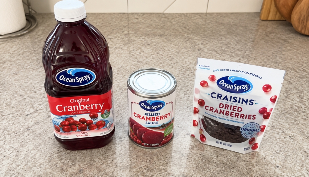 Cranberry juice bottle, canned sauce, and dried cranberries on kitchen counter