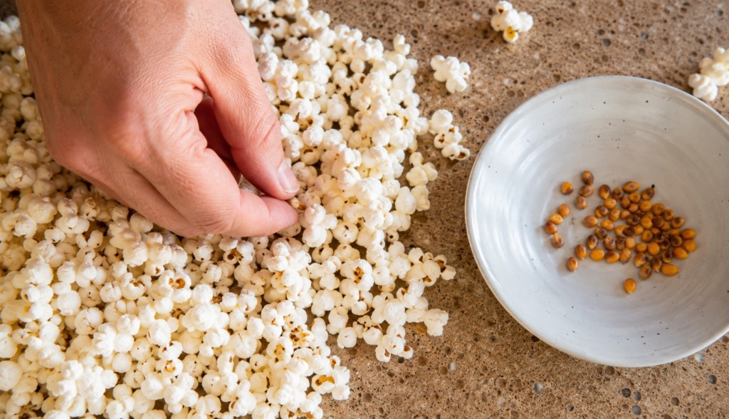 Hand sorting unpopped kernels out of popcorn on kitchen counter