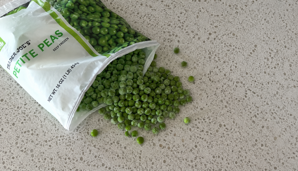 Bag of frozen peas spilling onto kitchen counter
