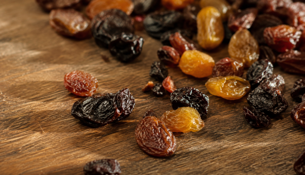 ChatGPT Image Jun 8, 2026, 03_33_01 PM Raisins and dried currants scattered on wooden kitchen table close-up