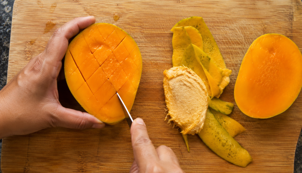 Mango pit and skin removed on cutting board during preparation
